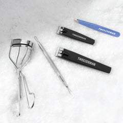 Eyelash Curler, combo clipper set, skin care tool and tweezer on a snow background