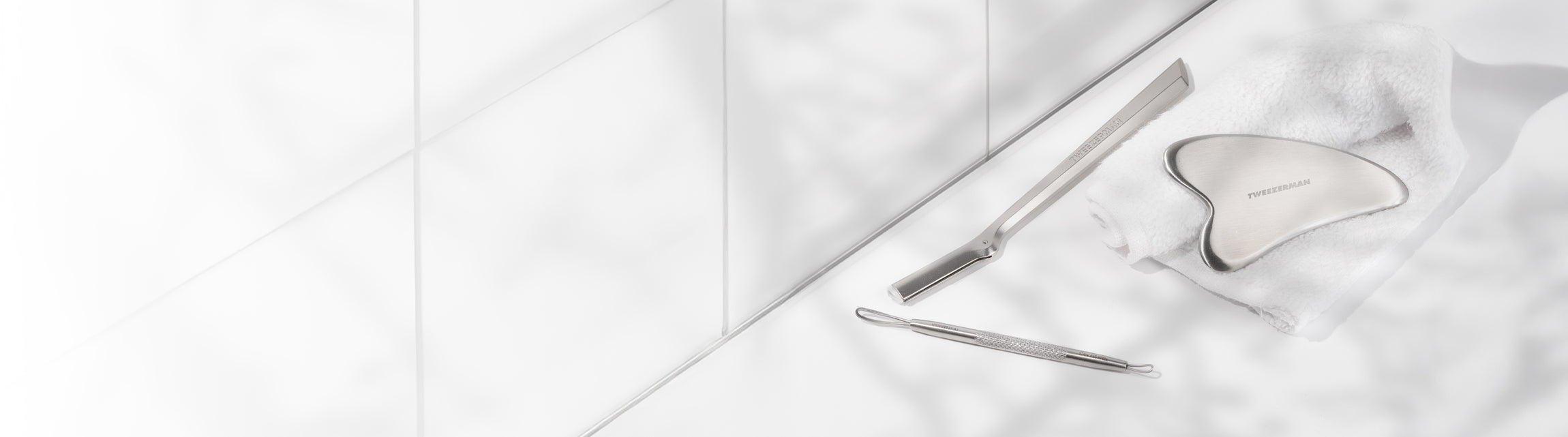 Facial Razor, Gua Sha and Whitehead remover tool on white tiles