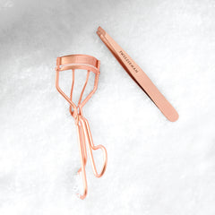 Rose Gold Eyelash Curler and Tweezer on a snow background