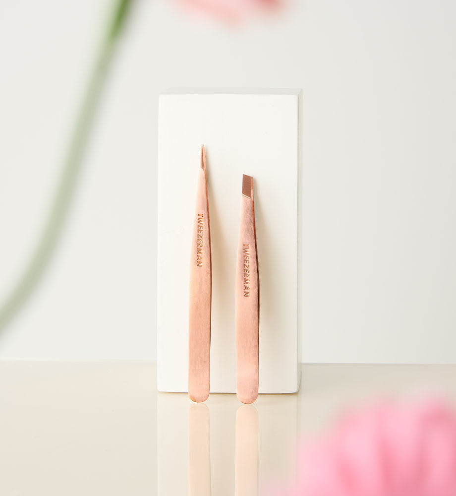 Rose gold tweezers on a white card with 'Tweezerman' branding against a light background.
