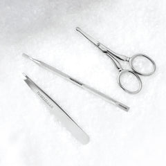 Stainless Steel Tools on a snow background, tweezer, pushy and facial hair scissors