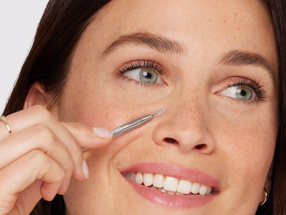 Model using the skincare tool to remove whiteheads and blackheads