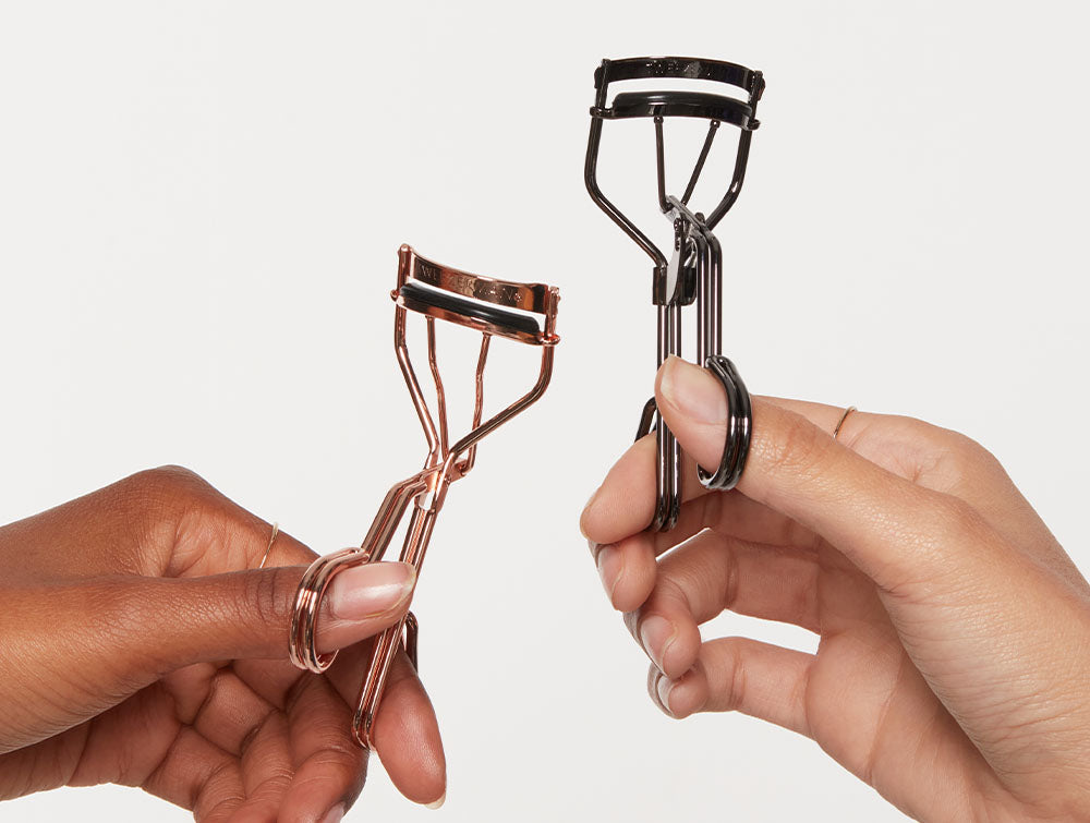 2 eyelash curlers held by the hands of 2 different people