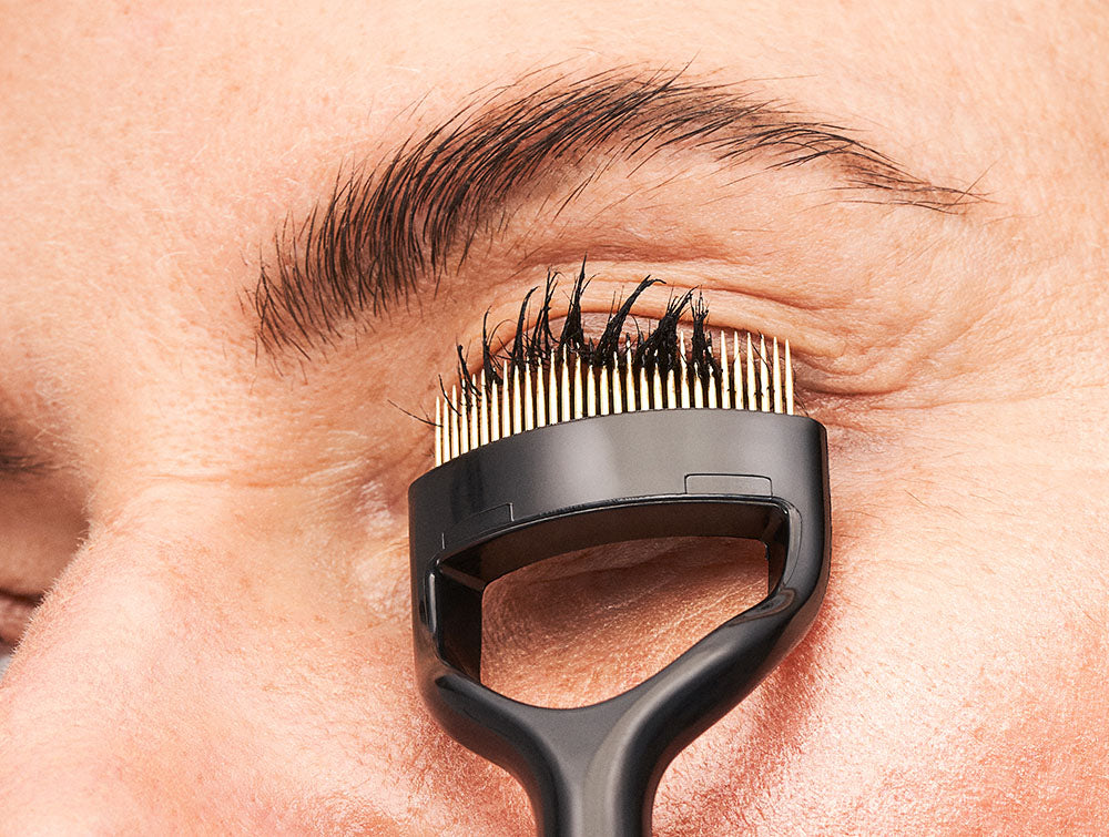 Eye close up using the ilashcomb on the lashes to separate mascara