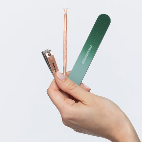 Model holding 1 dark green nail file and rose gold fingernail clipper and cuticle pushy
