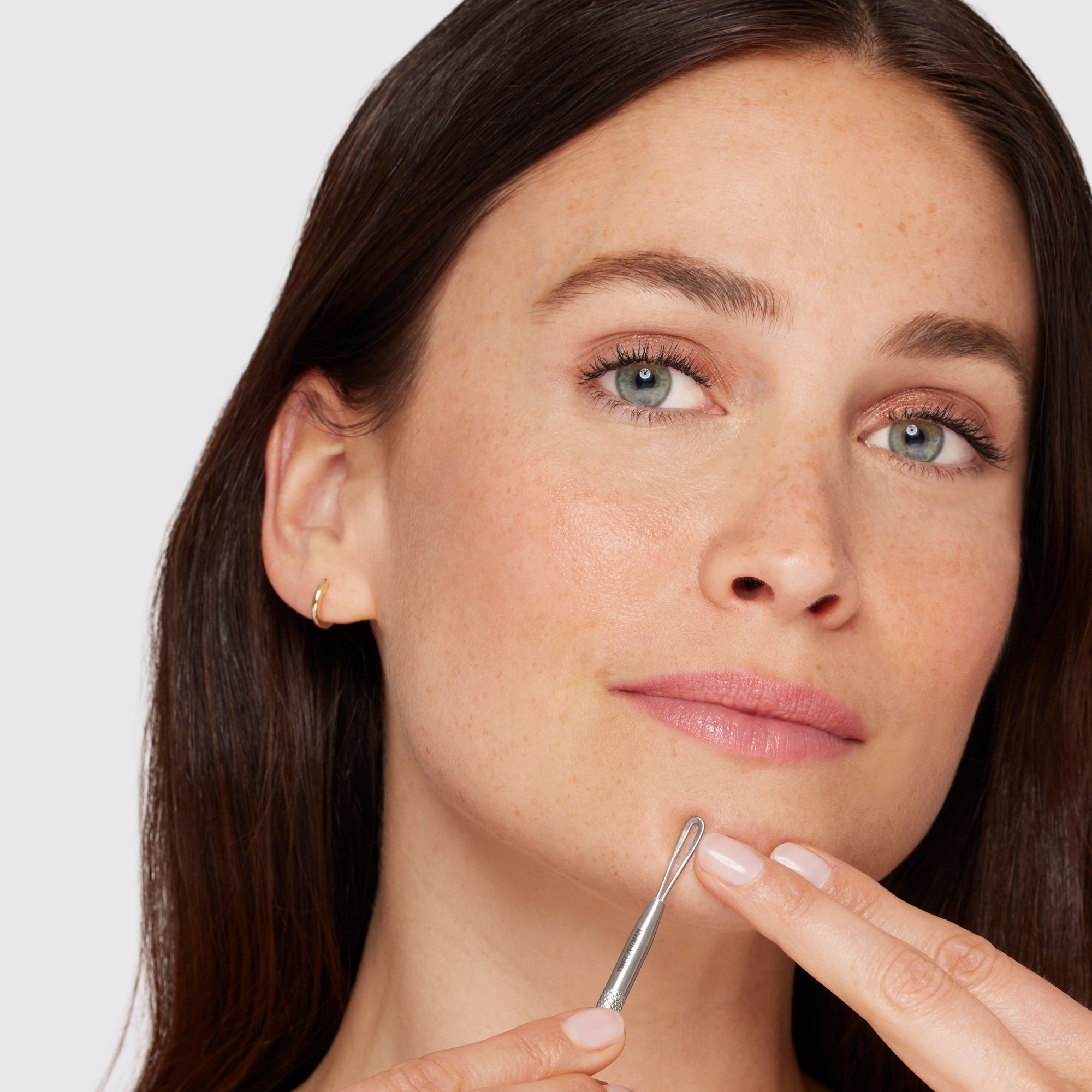 Model using long flat loop end of skincare tool